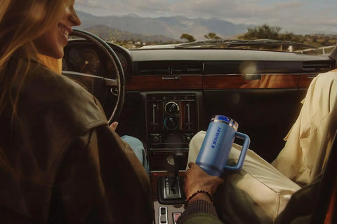 Solid Double Wall Vacuum Insulated Flip Straw Travel Tumbler With Secure Leakproof Lid Keeps Drinks Ice Cold All Day Long Rose Quartz Thirty Ounce Portable Cup For Gym Hiking And Daily Grind in a car cup holder.