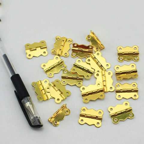 20 Pack Small Cabinet Door Hinges For Furniture Upgrade Heavy Duty Drawer Mounting Braces Smooth Swing Closet Cupboard Fittings Built Like A Tank Ultra Durable Steel Perfect For Diy Renovations And Home Makeovers. Gold small cabinet door hinges on white background with pen.