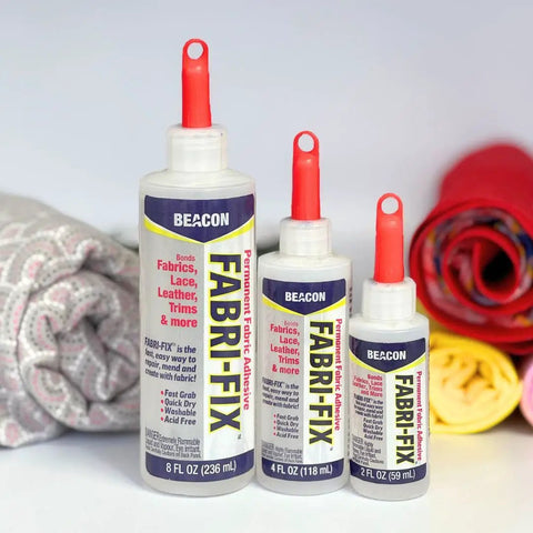 Fabri Fix Bonding Solution With Fast Grab And Quick Dry For Fabric Leather Suede Felt And Canvas Washable After Set No Heat No Mess Burn Free 8 Ounce Multimaterial Adhesive shown with rolls of fabric, various bottle sizes displayed.