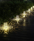 2 Pack Upgraded Solar Lanterns For Outdoor Use, 15 Lumens, Decorative bronze lights casting patterns on a wooden walkway.