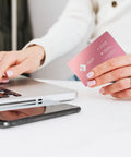 Person holding Colorful Aluminum Metal Business Card Blank near laptop, pink card, 3.38 x 2.12 inches, for laser engraving.