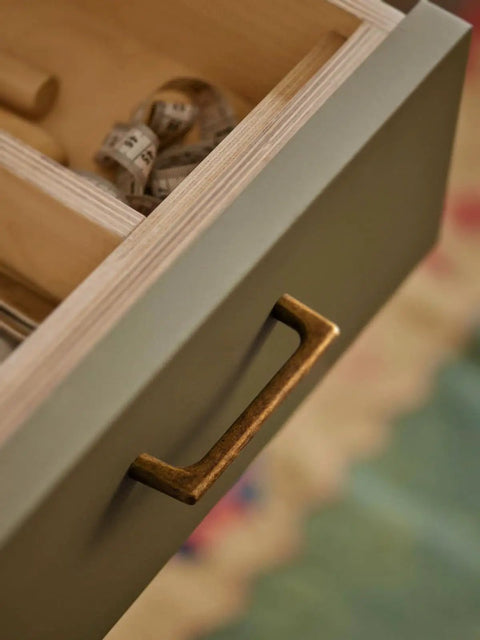 Close-up of vintage brass drawer pulls on open cabinet showing antique style handles for kitchen cabinets and dressers