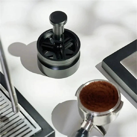 Killer Precision Rotary WDT Tool For Espresso Portafilter on a light surface next to a coffee portafilter with grounds.