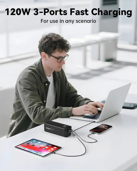 Person using 27000mAh 120W Fast Charging Power Bank With 3 Ports And Smart Display, charging laptop and phone simultaneously.