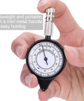 Rugged Mini Map Measuring Wheel For Dead Accurate Outdoor Distance Tracking And Trail Navigation Featuring Heavy Duty Alloy Build As Your Go To Campout Rig For Hiking Adventures Weekend Trips, held in hand with a mini metal handle.