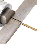 Wooden ring drill bit in brass color mounted in a metal collar drilling through wood.