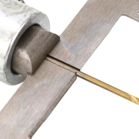 Wooden ring drill bit in brass color mounted in a metal collar drilling through wood.