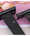 Close-up of black iron Beefy Heavy Duty T Shape Door Hinges With Screws 2 Inch, showing triangular design on pink background.