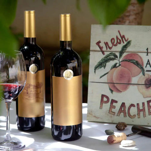 Premium Heat Shrink Wine Bottle Caps 100 Pack Flexible PVC Sealing Film on wine bottles with gold tops outdoors.