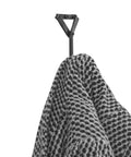 Heavy Duty Wrought Iron Coat Hook With A Distressed Bronze Look Hand Forged Wall Mount Rack Built Tough Rust Proof Construction hanging a black and white checked throw