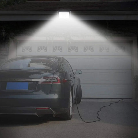 JUDYSSY Solar Floodlight Outdoor with 180° Angle Lighting Adjustable and Light Sensorremote Control LED illuminating a garage.