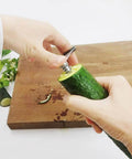 Close-up of hands using a 2-in-1 vegetable spiral peeler on cucumber; stainless steel blade