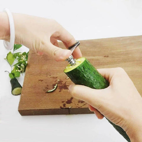 Close-up of hands using a 2-in-1 vegetable spiral peeler on cucumber; stainless steel blade