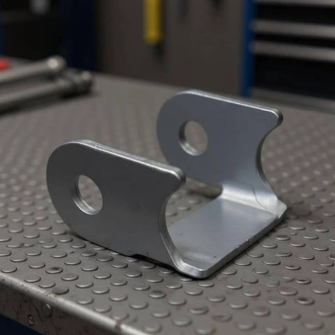Heavy Duty Swing Arm Bracket And Control Arm Bracket Shock Absorber Mount Kit For Custom Off Road Builds With Robust Steel Fabrication Hardware showing a close-up of steel bracket on workbench.