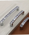 Crystal U Shaped Drawer Pull Handles in Bright Chrome with screws, set of three on wood surface