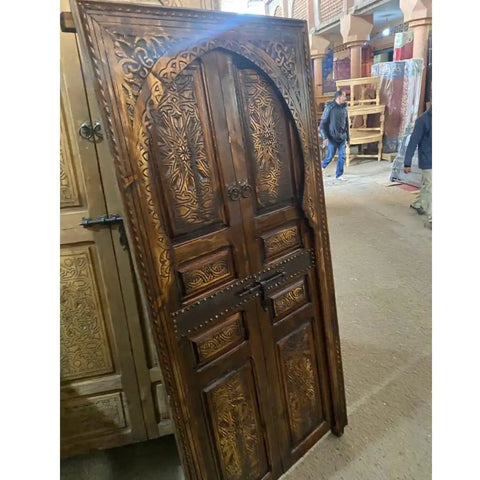 Hand Carved Barn Door With Brown Gold Finish Dope Look And Custom Size For Interior Exterior Use Double Or Single Sliding Or Hinged Front Door Antique And Modern Style Made To Order shows detailed carvings in a workshop setting.