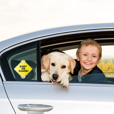 Baby On Board Car Sign Pack, Two Window Stickers With Super Strong Double Suction Cups installed on car window next to child and dog.