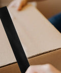 Person applying Heavy Duty Waterproof Repair Tape 50m By 50mm Rubberized Sealant For Leaks on a cardboard box