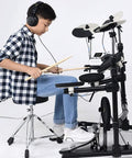 Adjustable Height Drum Stool With Double Brace Frame And Knockout Comfort For Tight Beat Sessions Anti Slip Rubber Feet Versatile Music Throne Built Tough In Sleek Black Finish 55 Cm Wide, shown in use by a young drummer wearing headphones.