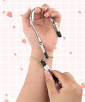 Hand using Three Piece Bracelet Helper Tools Set With Retractable Anti Slip Clip to fasten bracelet on wrist against strawberry background.