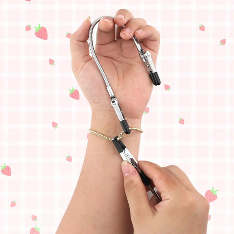 Hand using Three Piece Bracelet Helper Tools Set With Retractable Anti Slip Clip to fasten bracelet on wrist against strawberry background.