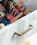 Open drawer with Six Pack 5 Inch Champagne Bronze Knurled Cabinet Pulls With Crosshatch Knurling, showing colorful storage