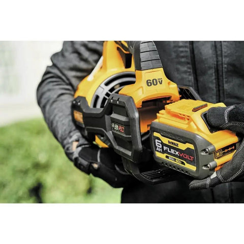 Person holding 60V Max FlexVolt Cordless Handheld Leaf Blower, showing battery compartment, outdoor setting