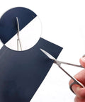 Stainless steel precision craft scissors cutting dark blue vinyl sheet; close-up view