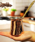 Hand holding Turkish Coffee Pot For Stovetop Copper Water Boiler And Milk Warmer, hammered copper with brass handle