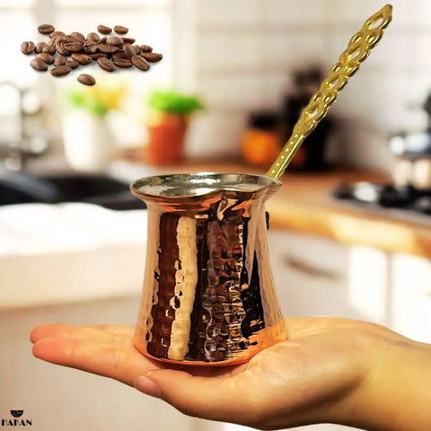 Hand holding Turkish Coffee Pot For Stovetop Copper Water Boiler And Milk Warmer, hammered copper with brass handle