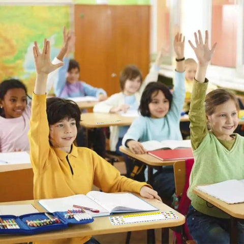 Children in a classroom with 40 Pack Clear Adhesive Desk Nameplate Pockets, 13.5 by 4.7 Inch Self Adhesive Name Tag Sleeves on desks.