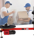 Built Different Heavy Duty Electric Pallet Wrapping Machine Used for sealing boxes with workers at a logistics dock.