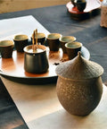 Retro Styled Sealed Ceramic Jar For Loose Tea And Coffee Beans, brown color, decorative lid, placed on a tabletop with tea set.