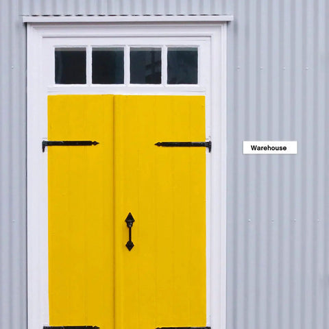 Yellow door on corrugated metal wall with 'Warehouse' sign.