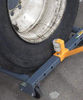 Rolling wheel dolly with blue steel frame and orange clamp supporting a large tire