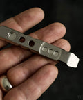 Hand holding Titanium Ti Pry Mini Pry Bar Keychain EDC Pocket Pry Tool With Bottle Opener in 6Al4V titanium construction.