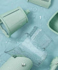 Le d Affaires 5-in-1 kitchen cheese grater and slicer set in green; disassembled plastic components with a clear pitcher.