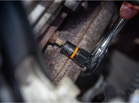 A mechanic uses a socket wrench with a 28 Piece 1/4 Inch And 3/8 Inch Drive Bolt Biter Impact Extraction Socket Set With Laser Etched Size Markings Black Oxide Finish For Corrosion Resistance And Up To Ten Times Longer Impact Life For Quick Pro Level Fastener Rescue In The Garage in a garage.