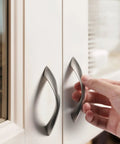 Brushed Nickel Cabinet Pulls 3 Inch Arch Twisted Silver Handles For Drawers And Cabinets Kitchen Cupboard Dresser Bathroom Zinc Alloy Heavy Duty Hardware being installed on white cabinet doors.