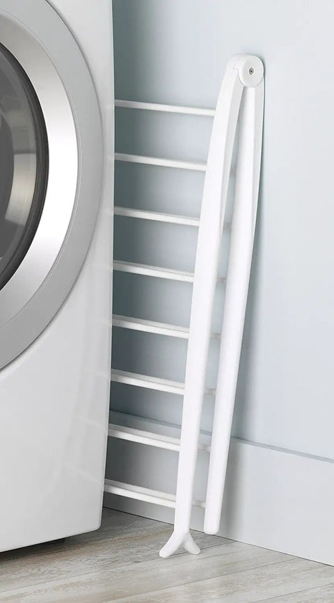 Freestanding Indoor Clothes Drying Rack Foldable Garment Hanger Compact Space Saving Design Lightweight White Finish leaning against the wall.
