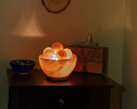 Fire Bowl Salt Lamp With Crystal Massage Balls Handcrafted From Pakistan on wooden base, warm glow on table, home decor.