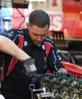 Mechanic working on engine wearing Heavy Duty Shop Apron Built Tough With Liquid Resistant Fabric And A Boatload Of Tool Pockets