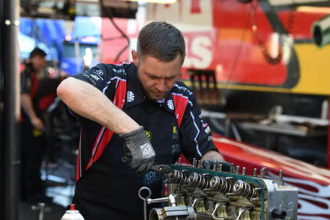Mechanic working on engine wearing Heavy Duty Shop Apron Built Tough With Liquid Resistant Fabric And A Boatload Of Tool Pockets