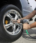 Person using Badass Heavy Duty Black Rubber Air Compressor Hose 3/8 Inch By 50 Feet 300 Psi on a car tire.