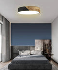 Bedroom with round wood grain black flush mount ceiling light, 12 inch, 24W LED fixture, warm white 3000K, sleek modern minimalist design.