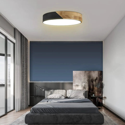 Bedroom with round wood grain black flush mount ceiling light, 12 inch, 24W LED fixture, warm white 3000K, sleek modern minimalist design.