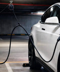 Straight Up Genius For Home EV Charging With This Overhead Retractable Cord Reel connected to a white electric vehicle in a garage.