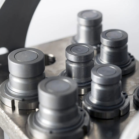 Gray metal 3/8-inch flat-face hydraulic quick-connect couplers with dust caps mounted on a manifold