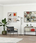 Spoke Wheel Pulley Floor Lamp With Metal Shade In Aged Steel Finish for industrial living room decor, next to artwork and armchair.