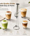Rechargeable Milk Frother With Stand Electric Whisk Foam Maker USB C Two Speed Handheld Drink Mixer For Coffee Latte Cappuccino Matcha Drinks Silver Finish on a table with four foam-topped beverages